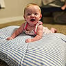 baby, child, infant, smiling, happy, sitting, portrait, indoors, cushion, pillow, striped, blue_and_white, dress, floral, carpet, furniture, living_room, background, warm_lighting, face