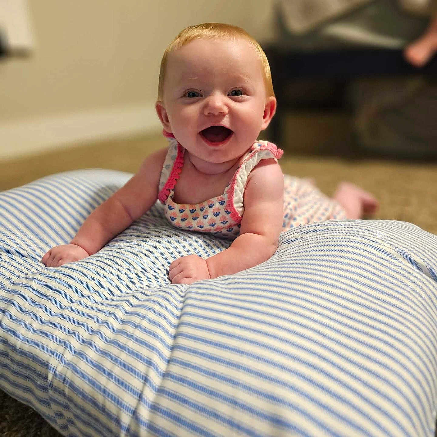 Emberly joined the competition — help win amazing prizes! baby, child, infant, smiling, happy, sitting, portrait, indoors, cushion, pillow, striped, blue_and_white, dress, floral, carpet, furniture, living_room, background, warm_lighting, face