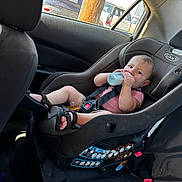 Carson is registered to the contest to win money with this photo: baby, car_seat, bottle, child, infant, car_interior, seatbelt, sandals, pacifier, window, sunlight, sitting, cute, person, child_safety, vehicle, seat, relaxing, daylight, casual