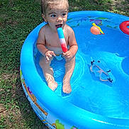 Xatthias is registered to the contest to win money with this photo: blue, child, colorful, fun, goggles, grass, happy, inflatable, outdoor, playing, pool, popsicle, sitting, skin, summer, sunlight, toddler, toy, water, wet