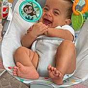 Joseph is registered to the contest to win money with this photo: baby, smiling, laughing, infant, baby_bouncer, toys, colorful, happy, cute, child, indoors, feet, hands, white_clothing, playful, face, person, home, carpet, relaxed