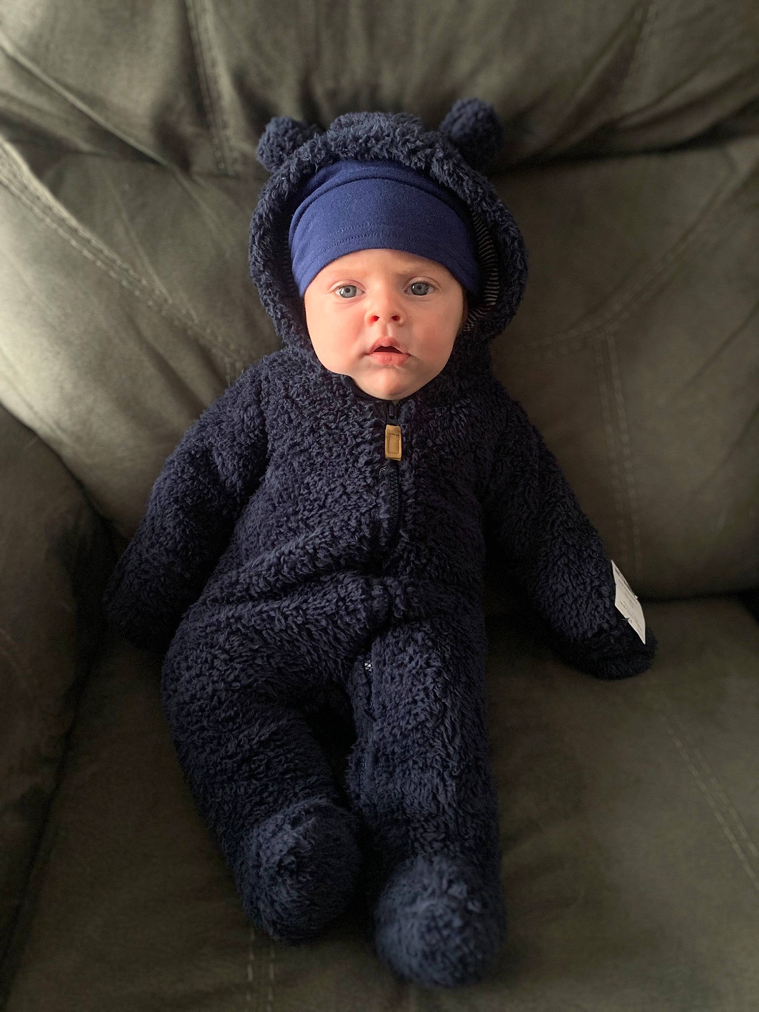 Landon is registered to the contest to win money with this photo: baby, baby_toddler_clothing, cheek, child, comfort, face, fashion_accessory, flash_photography, flooring, fur, grey, headwear, knit_cap, linens, mammal, outerwear, person, sitting, sleeve, toddler