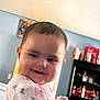 Ellie is registered to the contest to win money with this photo: baby, child, smile, indoor, onesie, face, person, cute, happy, sitting, furniture, shelf, bottle, toy, clothing, head, portrait, home, expression, infant