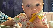 Elowyn is registered to the contest to win money with this photo: baby, blanket, blue_eyes, child, clothing, colorful, cozy, curtains, cute, face, hand, indoors, infant, light, person, popsicle_print, portrait, sitting, soft_toys, teething_toy