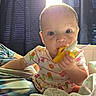 Elowyn is registered to the contest to win money with this photo: baby, child, teething_toy, blue_eyes, curtains, blanket, indoors, light, soft_toys, clothing, cute, person, infant, portrait, hand, face, sitting, colorful, popsicle_print, cozy