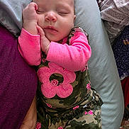 Elowyn is registered to the contest to win money with this photo: baby, sleeping, infant, camo_clothing, pink, flower_pattern, pillow, blanket, hand, cozy, resting, child, person, cute, soft_texture, indoor, portrait, peaceful, toddler, closeup
