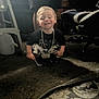 Michele is registered to the contest to win money with this photo: child, indoor, carpet, smiling, chain, shorts, black_shirt, squatting, furniture, chair, rug, person, happy, home, footwear, patterned_clothing, toy_or_object, legs, floor, blurred_background