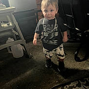 Michele joined the competition — help win amazing prizes! toddler, child, carpet, indoor, furniture, high_chair, office_chair, tshirt, shorts, sneakers, necklace, floor, cabinet, curious, standing, person, young_child, casual_clothing, dim_lighting, home_interior