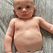 Julian joined the competition — help win amazing prizes! baby, infant, diaper, bare_chest, curious_expression, lying_down, gray_blanket, skin, child, cute, wide_eyes, puzzled, young, portrait, human, indoors, soft_light, toddler, one_person, closeup