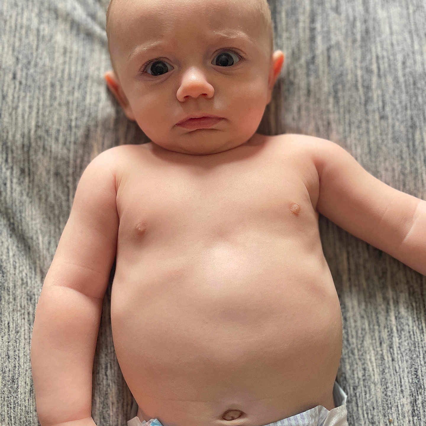 Julian joined the competition — help win amazing prizes! baby, infant, diaper, bare_chest, curious_expression, lying_down, gray_blanket, skin, child, cute, wide_eyes, puzzled, young, portrait, human, indoors, soft_light, toddler, one_person, closeup