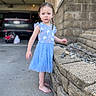 toddler, child, barefoot, blue_dress, stone_wall, rocks, outdoor, sidewalk, car, baby_carrier, curly_hair, braids, expression, concrete, daylight, person, standing, casual, curious, young_child