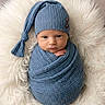 Ayaan is registered to the contest to win money with this photo: baby, blanket, blue, child, cozy, cute, expression, face, hands, infant, knit_hat, lying_down, newborn, portrait, sleepwear, small, soft_texture, warm, white_background, wrapped