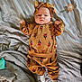 baby, infant, clothing, headwear, bed, blanket, pacifier, socks, pattern, face, person, lying_down, indoor, striped, fabric, soft, cute, child, expression, cozy