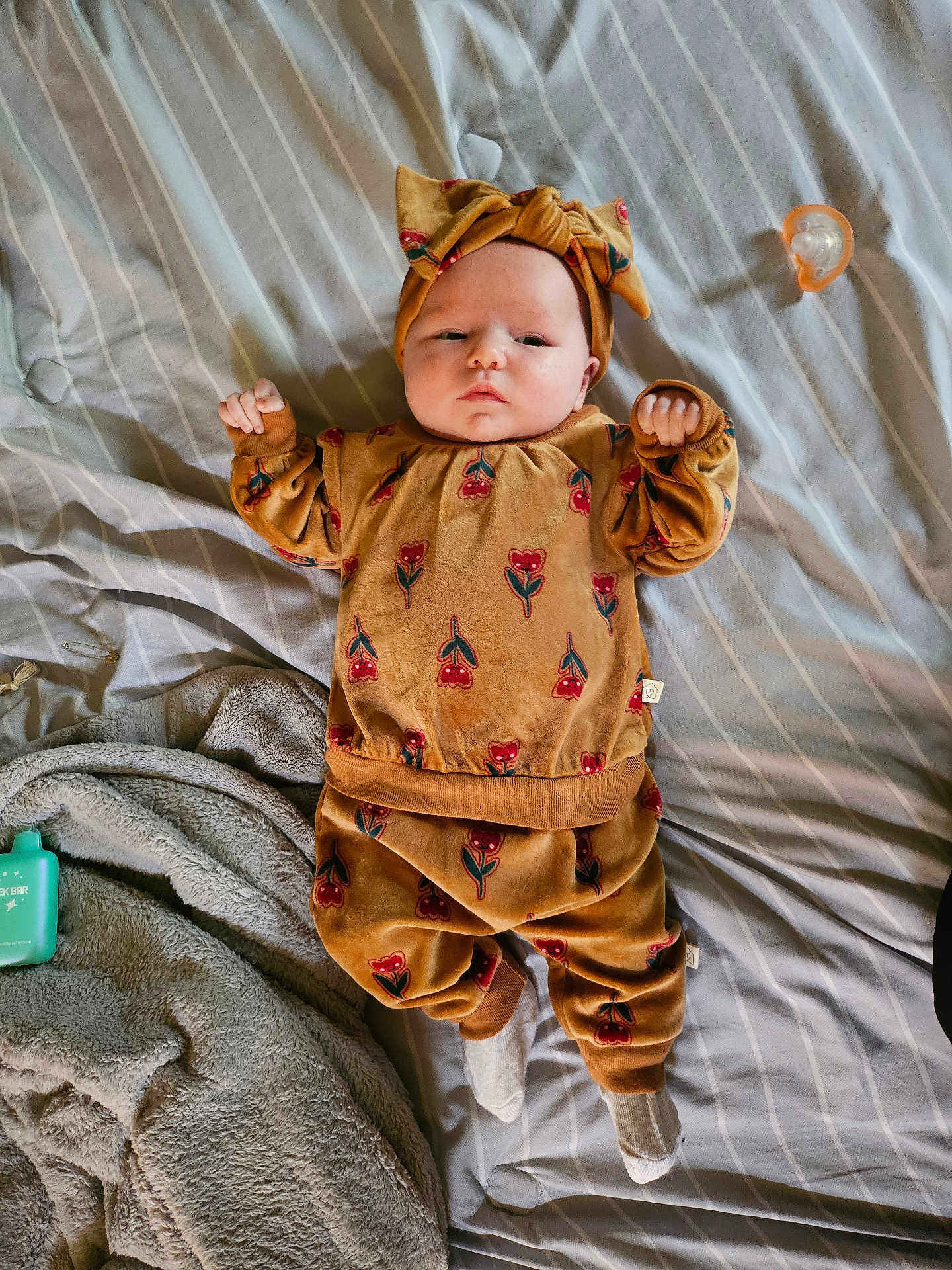 Lilly is registered to the contest to win money with this photo: baby, infant, clothing, headwear, bed, blanket, pacifier, socks, pattern, face, person, lying_down, indoor, striped, fabric, soft, cute, child, expression, cozy