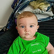 Benjamin joined the competition — help win amazing prizes! baby, child, green_shirt, blue_eyes, couch, blanket, indoor, portrait, sitting, clothing, camouflage_pants, face, cute, infant, expression, person, home, young, looking, casual