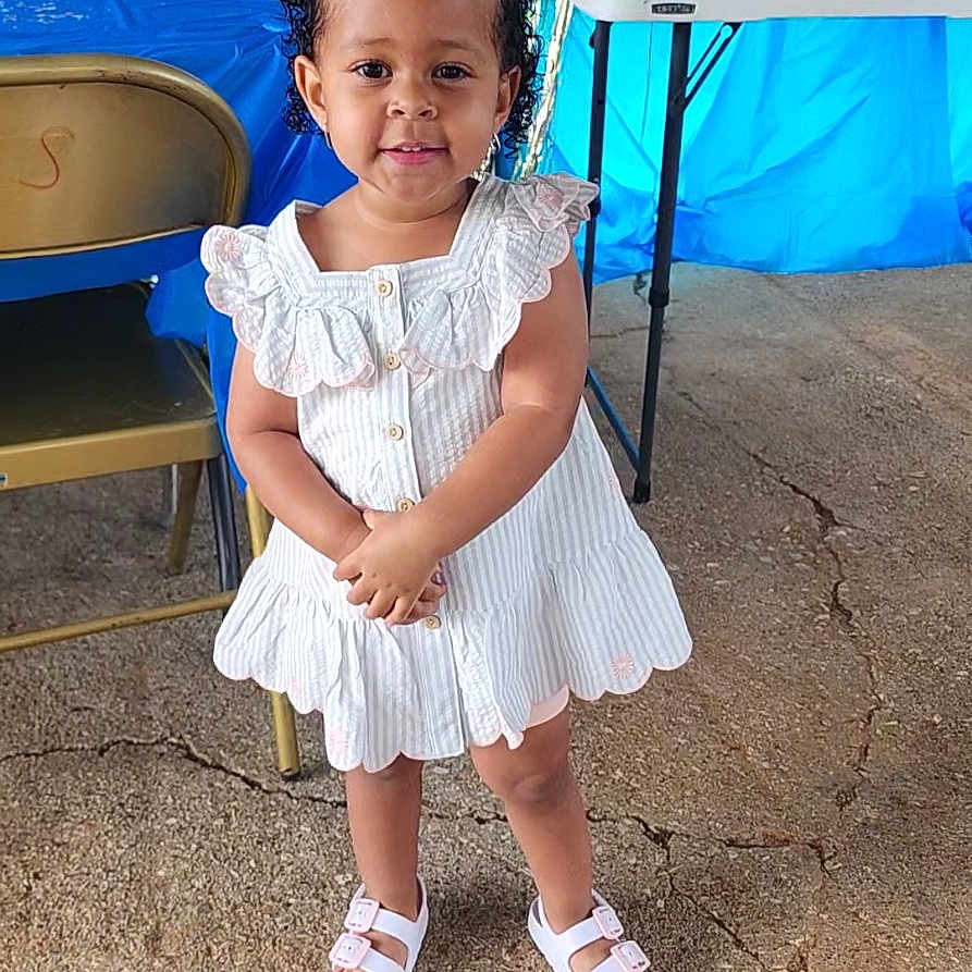 Zakariya is registered to the contest to win money with this photo: beachwear, child, clothing, dress, face, female, footwear, furniture, girl, happy, head, outdoors, person, photography, portrait, sandal, shoe, shorts, sitting, skirt