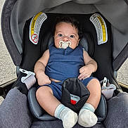 Miller James is registered to the contest to win money with this photo: baby, pacifier, car_seat, blue_outfit, socks, curly_hair, infant, child, seatbelt, sitting, indoors, closeup, cute, young_child, person, portrait, chicco, comfortable, wide_eyes, car