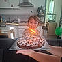 arm, birthday_cake, candle, celebration, child, clothing, furniture, hand, happy, indoor, kitchen, number_two, person, plate, powdered_sugar, shoes, smiling, sprinkles, table, toddler