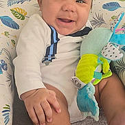 Sebastian joined the competition — help win amazing prizes! baby, smiling, infant, plush_toy, cushion, leaf_pattern, indoor, carpet, white_outfit, blue_suspenders, hand, foot, face, happy, child, cute, seated, home, decor, flower