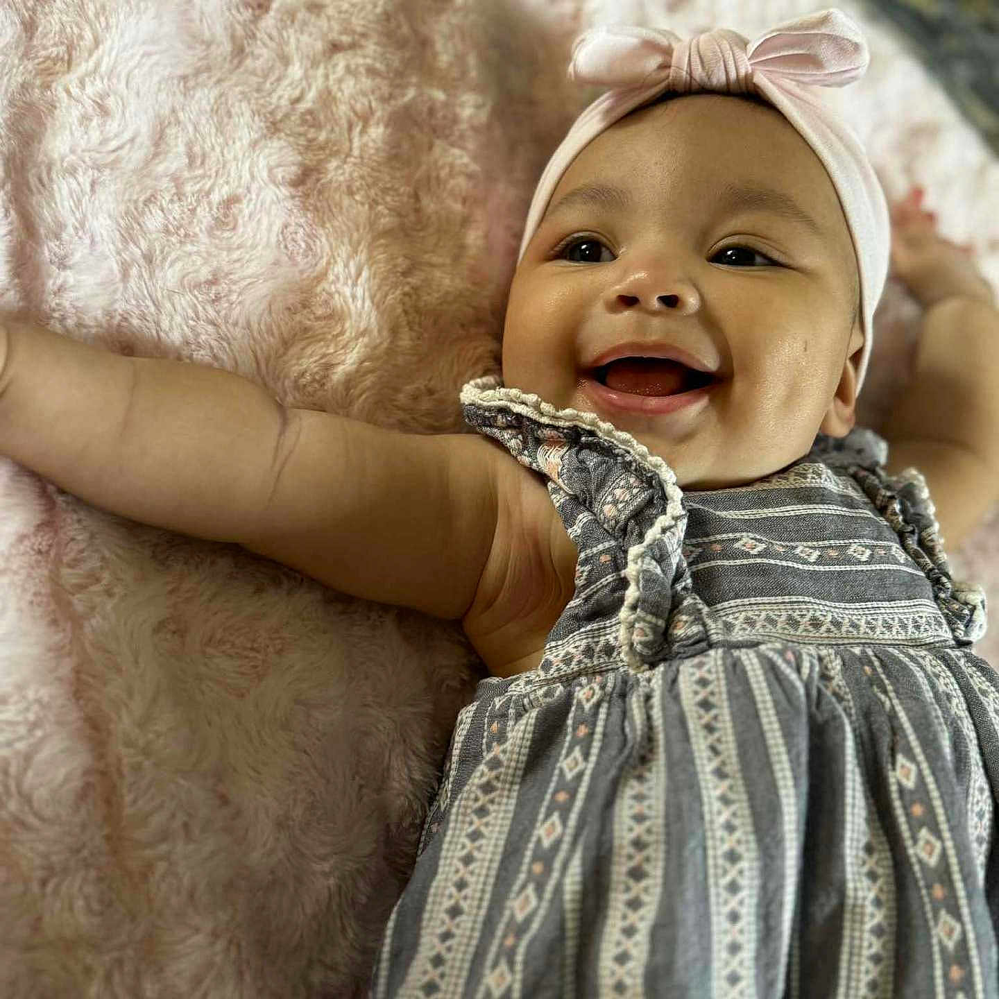 Isabella joined the competition — help win amazing prizes! arm, baby, blanket, cheerful, child, closeup, cute, dress, face, happy, headband, indoors, infant, lying_down, patterned_clothing, person, portrait, skin, smiling, textile