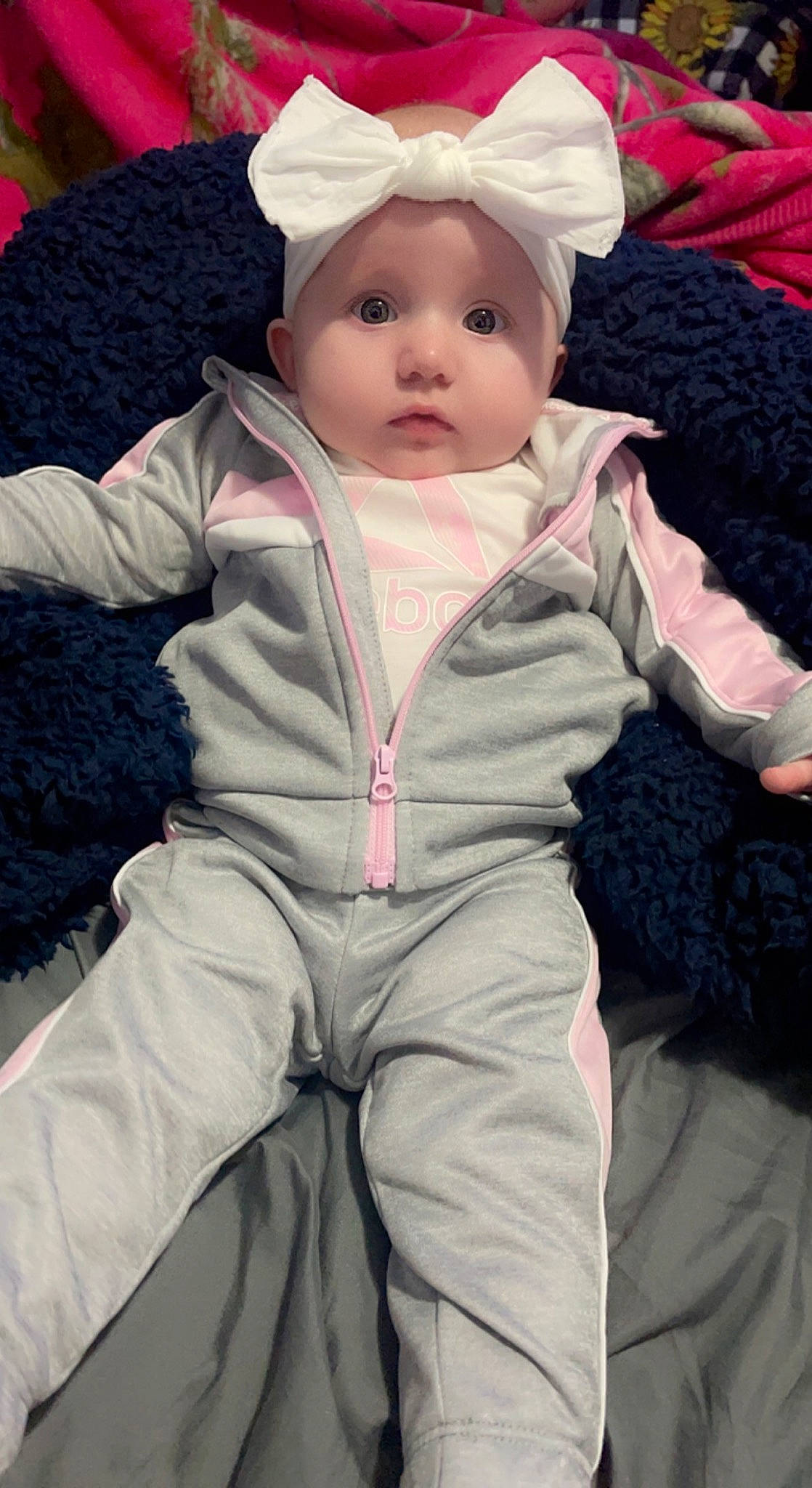 Kynlee is registered to the contest to win money with this photo: baby, baby_toddler_clothing, cheek, child, chin, comfort, eye, face, fur, head, linens, lip, outerwear, pink, sitting, skin, sleeve, toddler, white, wool