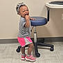 Symphony joined the competition — help win amazing prizes! toddler, child, indoor, playful, headband, shorts, sneakers, stool, floor, wall, smile, person, standing, gray_shirt, pink_shorts, socks, casual_clothing, young_child, cute, mischievous