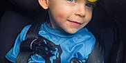 Logan is registered to the contest to win money with this photo: child, car_seat, seat_belt, blue_shirt, blonde_hair, stickers, smile, young_child, safety, portrait, indoor, cute, face, person, casual, happy, childhood, car_interior, close_up, playful