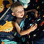 child, boy, bed, blanket, plush_toy, dinosaur, bedding, indoor, sleeping_area, light, face, hair, hand, blue, yellow, pattern, comfort, rest, portrait, young