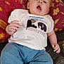 baby, blue_eyes, child, clothing, couch, curious, cute, fabric, face, hand, home, indoor, infant, jeans, lying_down, patterned_pillow, pillow, socks, toddler, white_shirt