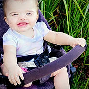 Adelina-Jo is registered to the contest to win money with this photo: baby, stroller, purple, smiling, grass, outdoor, child, happy, sitting, clothing, hand, foot, seatbelt, nature, green, person, infant, daylight, cute, portrait