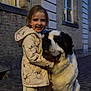 Zenna a rejoint le concours — aidez-le/la à gagner de superbes lots ! brick_wall, building, child, cobblestone, cute, dog, evening, footwear, happy, hoodie, hugging, jacket, leash, outdoor, pet, portrait, saint_bernard, smiling, street, window