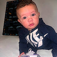 Zaylin is registered to the contest to win money with this photo: baby, child, sitting, hoodie, sneaker, shoe, white_surface, blackboard, handwriting, indoor, curious, young_child, clothing, footwear, portrait, face, casual, purple, bright_eyes, person