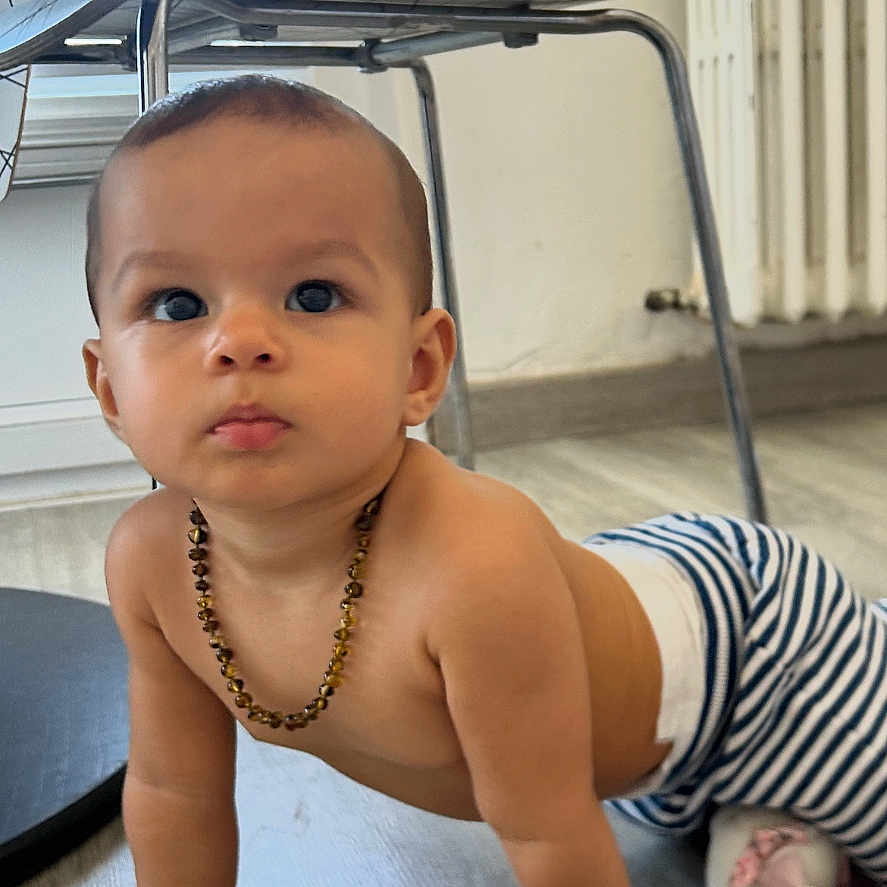 Adèle participe au concours pour gagner de l'argent avec cette photo : baby, beads, candid, child, crawling, curious, expression, floor, flooring, furniture, hands, head, home, indoor, modern_chair, necklace, person, striped_pants, wooden_floor, young_child