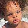 child, toddler, curly_hair, wet_skin, water_droplets, blue_object, outdoor, sunlight, face, eyes, hands, playing, summer, skin, portrait, expression, closeup, baby, person, nature