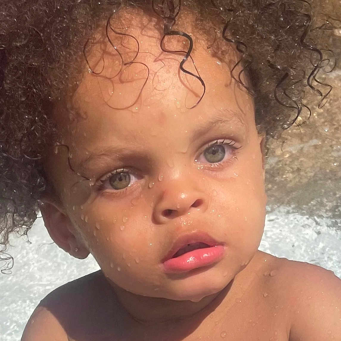 Sulieman joined the competition — help win amazing prizes! baby, blue_object, child, closeup, curly_hair, expression, eyes, face, hands, nature, outdoor, person, playing, portrait, skin, summer, sunlight, toddler, water_droplets, wet_skin