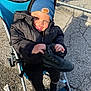 Sulieman joined the competition — help win amazing prizes! toddler, child, stroller, black_jacket, blue_beanie, football_patch, boot, smile, outdoor, sunlight, shadow, pavement, wheel, clothing, person, happy, holding, sitting, winter, cold_weather