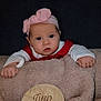 baby, infant, child, headband, bow, blanket, plush_blanket, wooden_plaque, milestone_sign, two_months, portrait, studio_photo, dark_background, hands, face, eyes, neutral_expression, red_outfit, cozy, prop