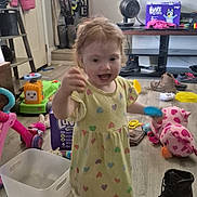 Amethyst is registered to the contest to win money with this photo: boot, child, clothing, diaper_box, fan, floor, happy, heart_pattern, indoor, living_room, messy, person, pink_jacket, plastic_container, playtime, shelf, shoes, toddler, toy, yellow_dress