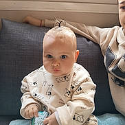 Thaïs participe au concours pour gagner de l'argent avec cette photo : baby, child, couch, sweatshirt, topknot, brush, indoor, person, sitting, cute, face, hand, clothing, expression, hair, toy, blanket, young_child, casual, home