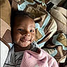 baby, blanket, bedspread, smile, infant, striped_clothing, face, indoors, child, comfort, patterned, fabric, person, cute, lying_down, soft_light, happy, young_child, cozy, portrait