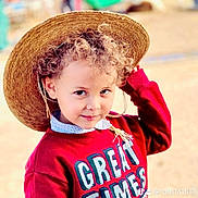 Rakan is registered to the contest to win money with this photo: child, curly_hair, straw_hat, red_sweater, outdoor, portrait, smiling, cute, young, playful, person, fashion, casual_wear, face, headwear, childhood, happy, daylight, fun, looking_at_camera