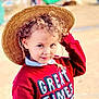 child, curly_hair, straw_hat, red_sweater, outdoor, portrait, smiling, cute, young, playful, person, fashion, casual_wear, face, headwear, childhood, happy, daylight, fun, looking_at_camera