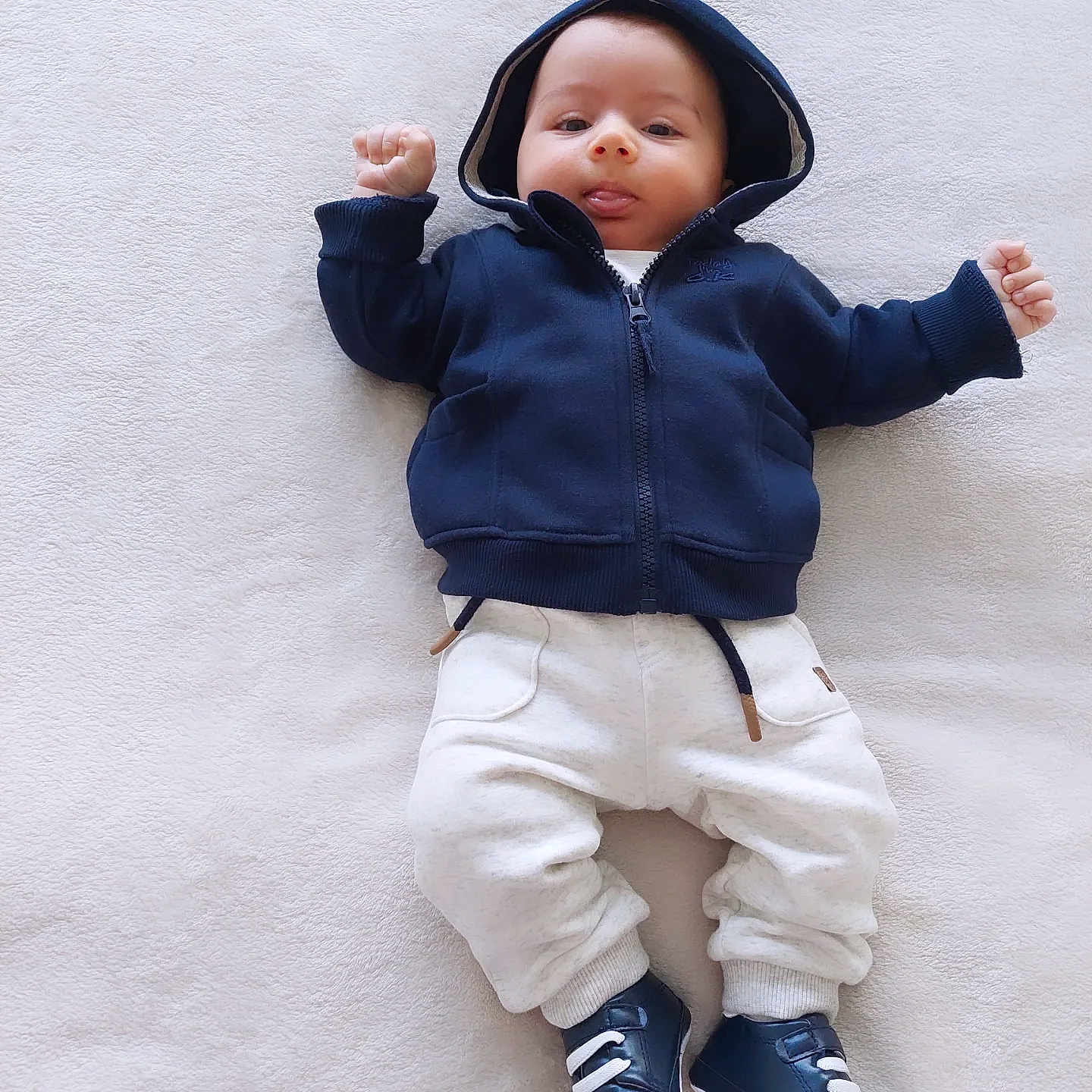 Gagik participe au concours pour gagner de l'argent avec cette photo : baby, child, infant, hoodie, blue_clothing, white_pants, shoes, tongue_out, lying_down, blanket, cute, small_hands, casual_wear, comfortable, soft_texture, indoors, playful, smiling, young, portrait