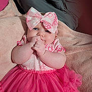 Adeline is registered to the contest to win money with this photo: baby, infant, pink_bow, tutu, dress, blanket, cute, hands, face, blue_eyes, soft_texture, indoor, child, adorable, clothing, lying_down, headband, portrait, skin, smiling