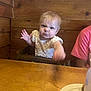 baby, toddler, child, wood, high_chair, table, plate, cup, person, face, expression, furniture, indoor, clothing, pink_shirt, light, hair, cute, funny_face, restaurant