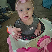 Layla is registered to the contest to win money with this photo: toddler, baby, headband, pink_flower, baby_walker, toy, unicorn_toy, striped_shirt, carpet, sofa, blanket, pet_bowls, water_dispenser, hand, face, blue_eyes, indoor, child, cute, home