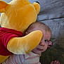 Layla is registered to the contest to win money with this photo: baby, plush_toy, winnie_the_pooh, stuffed_animal, child, couch, striped_shirt, indoor, hug, soft_toy, cute, face, hand, toddler, comfort, home, furniture, person, yellow, red_shirt