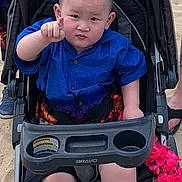 Jaydan Lau is registered to the contest to win money with this photo: beach, blue_shirt, casual, child, expression, family, footwear, hand, mohawk, outdoor, person, pointing, sand, shorts, stroller, summer, sunny, toddler, toy, vacation
