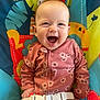 Lily is registered to the contest to win money with this photo: baby, child, infant, smiling, happy, play_seat, colorful, patterned, floral_clothing, onesie, straps, indoor, cute, portrait, young_child, person, joyful, bright_colors, seated, playful