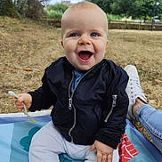 Liam participe au concours pour gagner de l'argent avec cette photo : baby, child, smiling, outdoor, grass, blanket, jacket, pants, fork, happy, person, blue_eyes, sitting, daylight, nature, trees, footwear, casual, park, joy